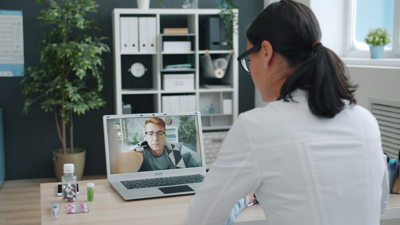 Doctor engaged in a video call with patient, discussing health online.